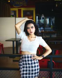 Portrait of young woman standing against wall