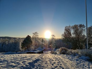 Snow covered field against sky during winter