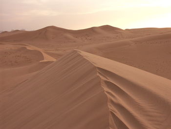 Sand dunes in desert against sky