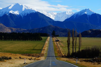 Road leading towards mountains against sky