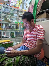 Young man looking away while sitting in store