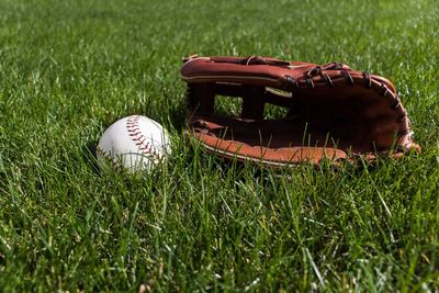 Close-up of baseball glove and ball on grass