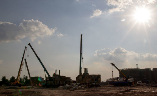 Cranes at construction site against sky during sunset