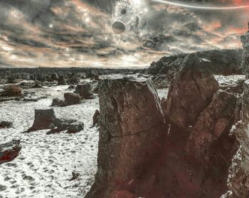 Close-up of rocks at beach against cloudy sky