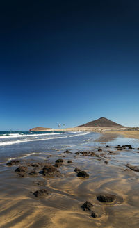 Scenic view of beach against clear blue sky