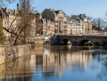 Bridge over river by buildings in city against sky