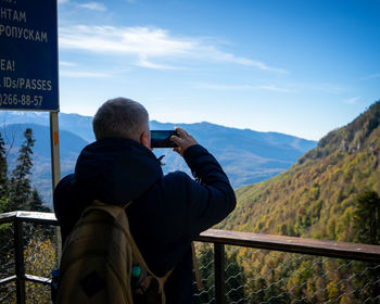 Rear view of man photographing on mountain