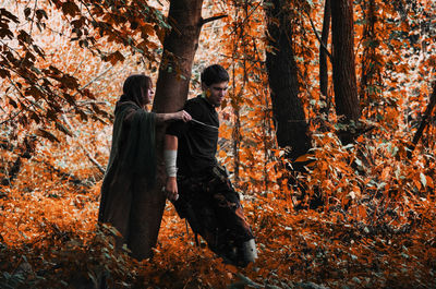 Rear view of man amidst trees in forest during autumn