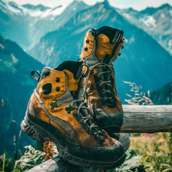 Low angle view of yellow hiking boots against mountain range view in background 