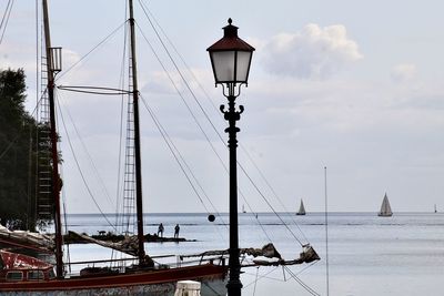 Street light by sea against sky