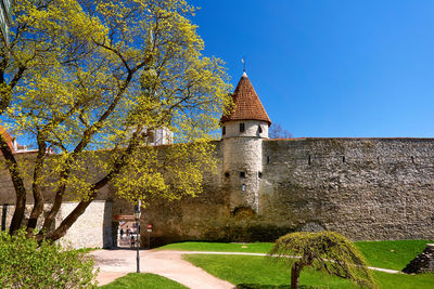 Built structure by trees against clear blue sky