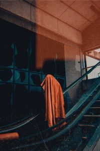 Person covering face with fabric while standing on escalator