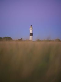 Low angle view of lighthouse by building against sky