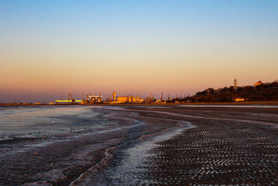 Road by city against clear sky during sunset