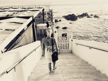 Rear view of woman walking by sea