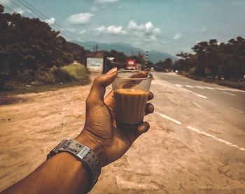 Midsection of man holding ice cream against sky