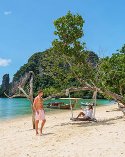 Rear view of woman standing at beach against clear blue sky