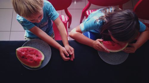 High angle view of siblings eating watermelon at home