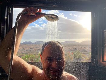 Portrait of man having shower against window