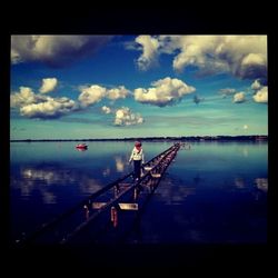 Pier in sea against cloudy sky