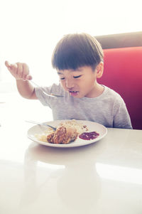 Close-up of boy having food at table