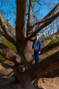 Full length of boy on tree trunk