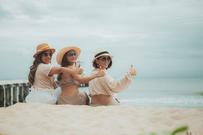 Three asian woman sitting on vacation sea beach with happinessw emotion