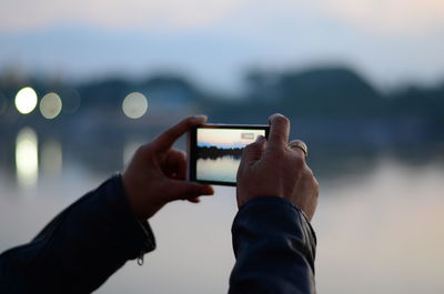 Midsection of man using mobile phone against sea