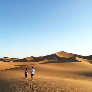 People on desert against clear sky
