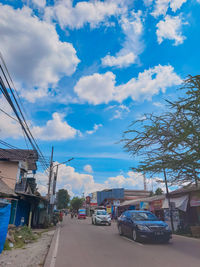 Cars on road by buildings against sky