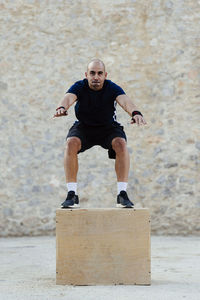 Man practicing crossfit jumping into a plyometric box.