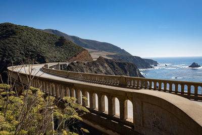 Bridge over sea against clear blue sky