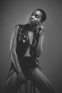 Young woman sitting on stool in leather vest