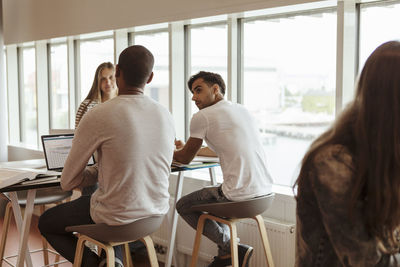 Multi-ethnic university students discussing while studying at cafeteria