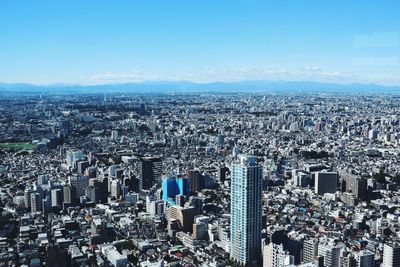 High angle view of modern buildings in city against blue sky