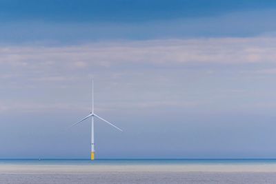 Wind turbines in sea against sky