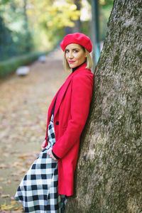 Portrait of young woman standing on tree trunk