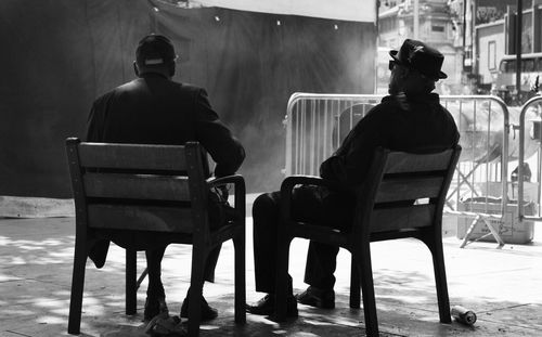 Rear view of men sitting on chairs on street