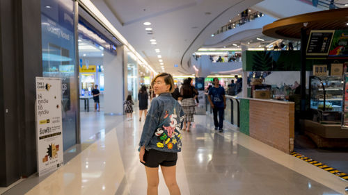 Rear view of woman standing on corridor at shopping mall