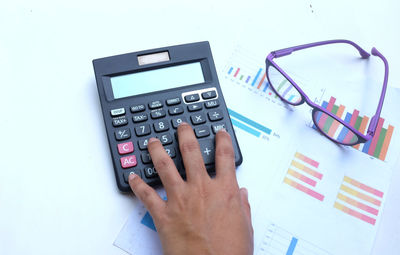 Cropped hand using calculator on table