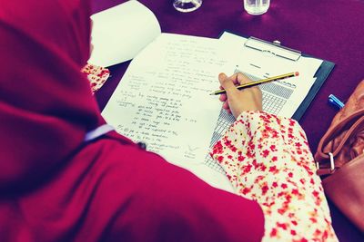 High angle view of woman writing on paper