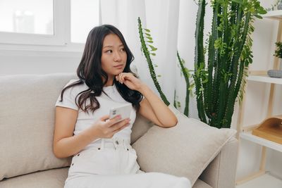 Portrait of young woman sitting on sofa at home