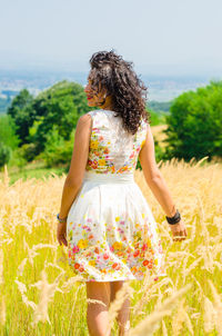 Rear view of woman standing on field against sky