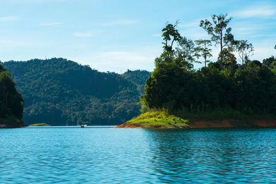 Scenic view of lake by trees against sky