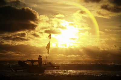 Silhouette man by sea against sky during sunset