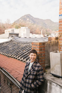 Portrait of smiling woman on roof against building