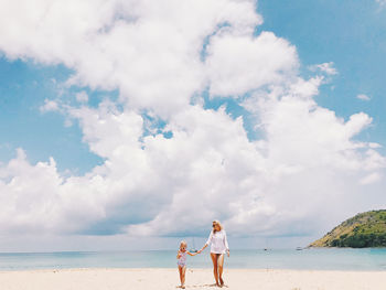 Woman standing on beach against sky