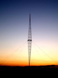 Silhouette of electricity pylon against clear sky