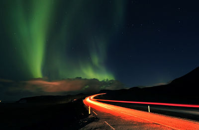 Light trails on road against sky at night