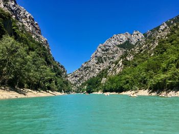 Scenic view of sea and mountains against clear blue sky